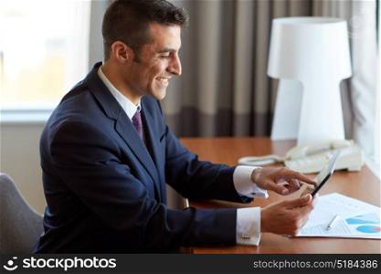 business, people and technology concept - businessman with tablet pc computer and papers working at hotel room. businessman with tablet pc working at hotel room