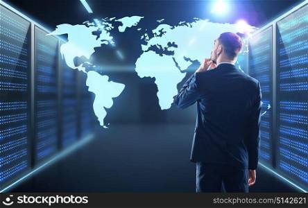 business, people and technology concept - businessman with virtual world map projection over server room background. businessman with world map projection in corridor