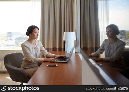 business, people and technology concept - businesswoman typing on laptop at hotel room. businesswoman typing on laptop at hotel room