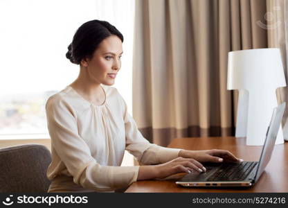 business, people and technology concept - businesswoman typing on laptop at hotel room. businesswoman typing on laptop at hotel room