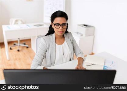 business, people and technology concept - businesswoman with computer, notebook and papers working at office. businesswoman with computer working at office