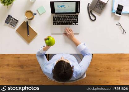 business, people and technology concept - businesswoman with laptop computer and green apple working at office. businesswoman with apple and laptop at office