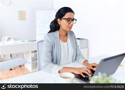 business, people and technology concept - businesswoman with laptop computer working at office. businesswoman with laptop working at office