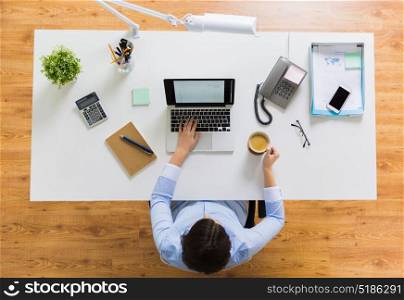 business, people and technology concept - businesswoman with laptop computer working at office and drinking coffee. businesswoman with laptop and coffee at office