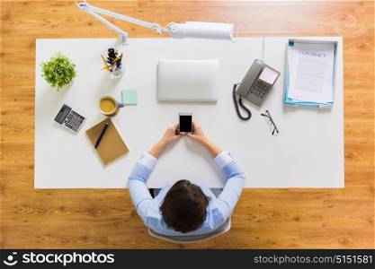 business, people and technology concept - businesswoman with smartphone working at office table. businesswoman with smartphone working at office