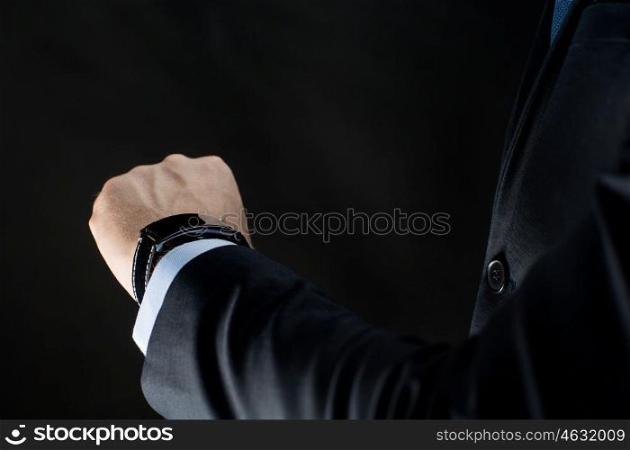 business, people and technology concept - close up of businessman hand with smart watch over black