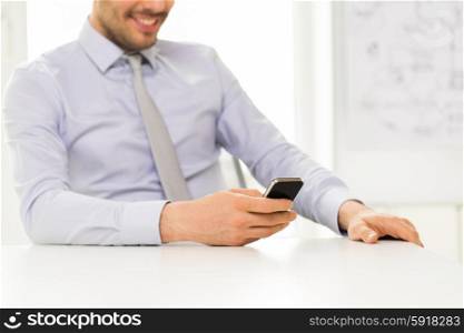 business, people and technology concept - close up of businessman hands with smartphone texting message at office