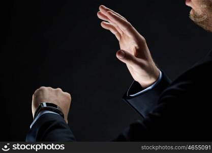 business, people and technology concept - close up of businessman hands with smart watch over black