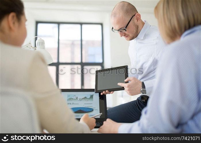 business, people and technology concept - close up of businessman showing tablet computer to colleagues at office. close up of business team with tablet pc at office