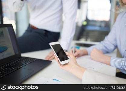 business, people and technology concept - close up of businesswoman showing smartphone to colleagues at office. business team with smartphone working at office