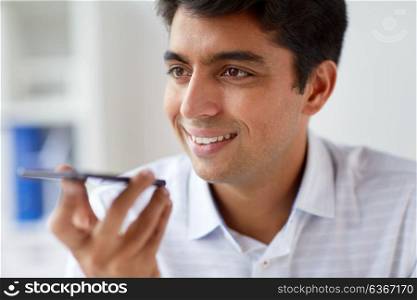 business, people and technology concept - close up of man using voice command recorder on smartphone at office. close up of man using voice recorder on smartphone