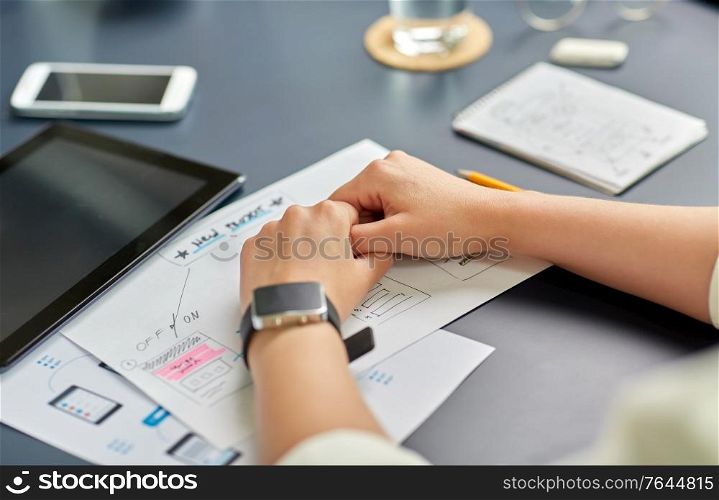 business, people and technology concept - close up of ui designer with mockups working on mobile app design at office. hands with mockup working on ui design at office