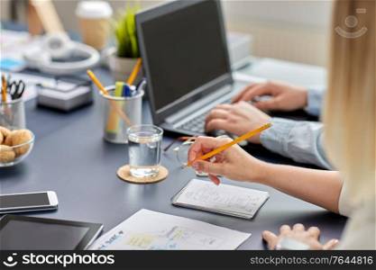 business, people and technology concept - close up of ui designer with notebook and pencil working on mobile app design at office. woman with notebook working on ui design at office