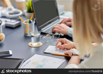 business, people and technology concept - close up of ui designer with notebook and eraser working on mobile app design at office. woman with notebook working on ui design at office