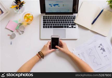 business, people and technology concept - hands with smartphone and laptop at office table. hands with smartphone and laptop at office table