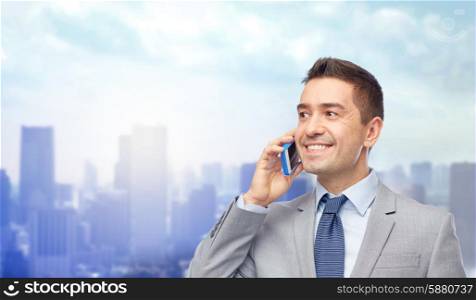 business, people and technology concept -happy businessman calling on smartphone over city background