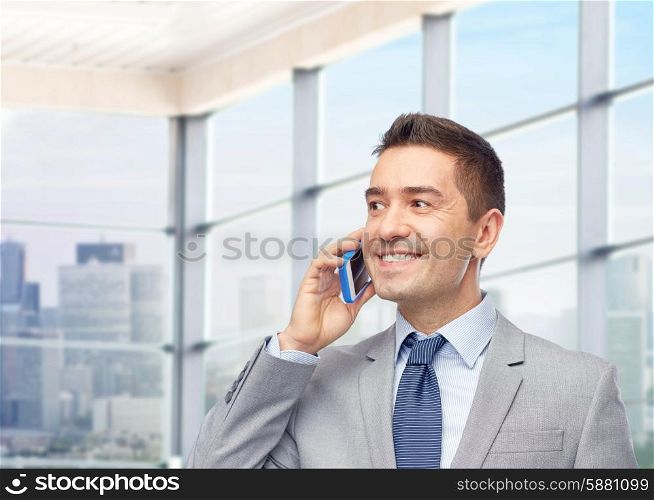 business, people and technology concept -happy businessman calling on smartphone over office room and window with city view background