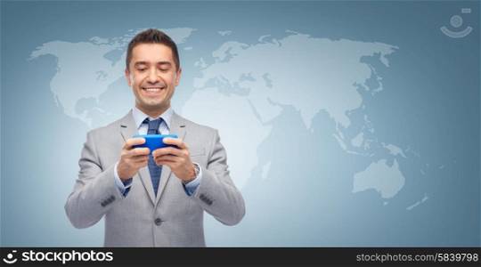 business, people and technology concept - happy businessman texting or reading message on smartphone over blue world map background