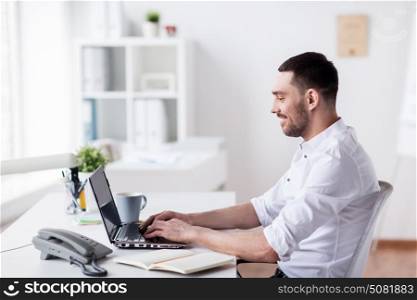 business, people and technology concept - happy businessman with laptop computer at office. happy businessman with laptop at office