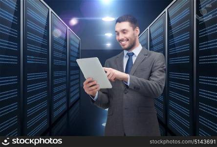 business, people and technology concept - happy smiling businessman in suit holding tablet pc computer over futuristic server room background. businessman with tablet pc over server room