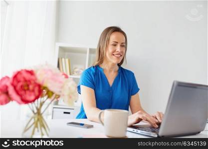 business, people and technology concept - happy smiling middle-aged woman with laptop computer working at home or office. happy woman with laptop working at home or office