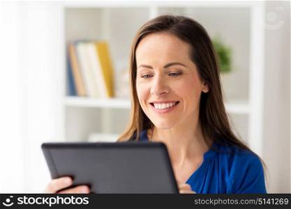 business, people and technology concept - happy smiling woman in glasses with tablet pc computer working at home or office. woman with tablet pc working at home or office