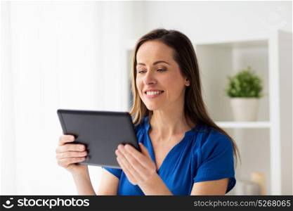 business, people and technology concept - happy smiling woman in glasses with tablet pc computer working at home or office. woman with tablet pc working at home or office