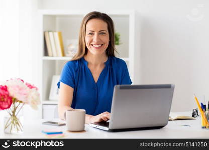 business, people and technology concept - happy smiling woman with laptop computer working at home or office. happy woman with laptop working at home or office