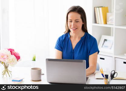 business, people and technology concept - happy smiling woman with laptop computer working at home or office. happy woman with laptop working at home or office