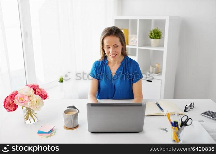 business, people and technology concept - happy smiling woman with laptop computer working at home or office. happy woman with laptop working at home or office. happy woman with laptop working at home or office