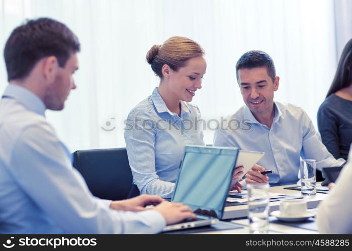 business, people and technology concept - smiling business team with laptop and tablet pc computer meeting in office