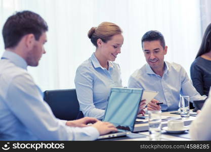 business, people and technology concept - smiling business team with laptop and tablet pc computer meeting in office