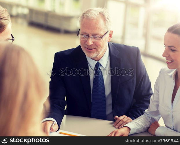 business, people and technology concept - smiling business team with laptop computer meeting in office. smiling business people meeting in office