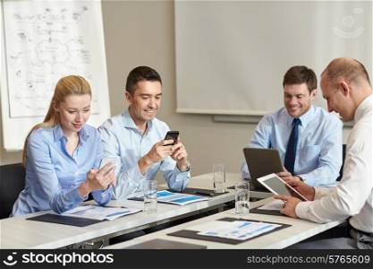 business, people and technology concept - smiling business team with smartphone and papers meeting in office