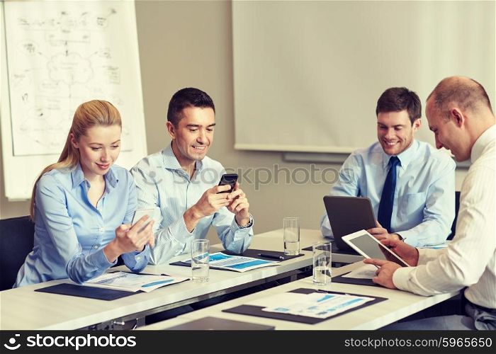 business, people and technology concept - smiling business team with smartphone and papers meeting in office
