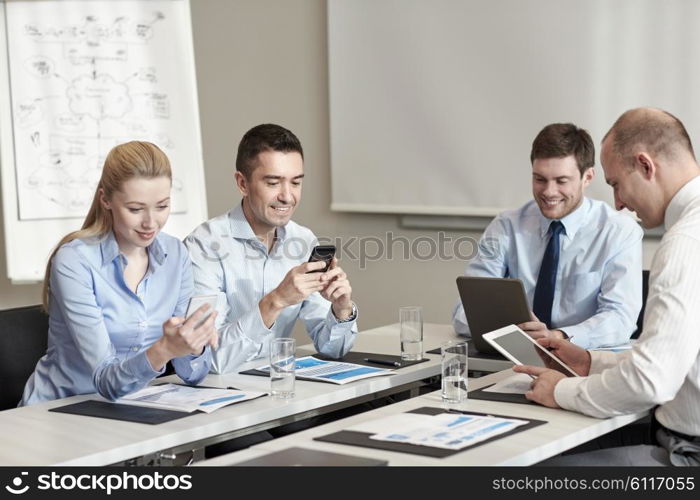 business, people and technology concept - smiling business team with smartphone and papers meeting in office