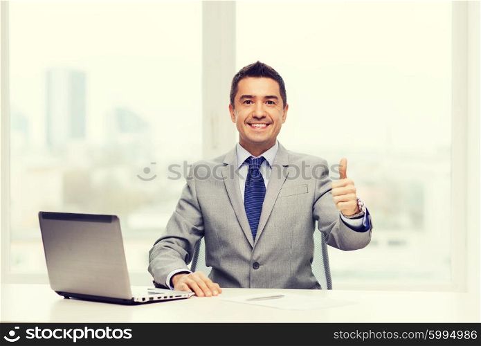 business, people and technology concept - smiling businessman in suit working with laptop computer in office