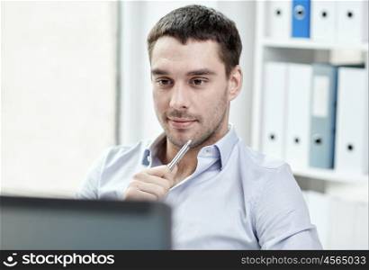 business, people and technology concept - young businessman with laptop computer at office