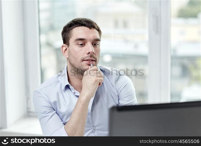 business, people and technology concept - young businessman with laptop computer at office