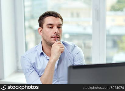 business, people and technology concept - young businessman with laptop computer at office