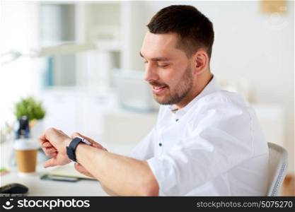 business, people and time concept - close up of happy smiling businessman with smartwatch at office. close up of businessman with smartwatch at office