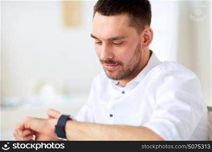 business, people and time concept - close up of happy smiling businessman with smartwatch at office. close up of businessman with smartwatch at office