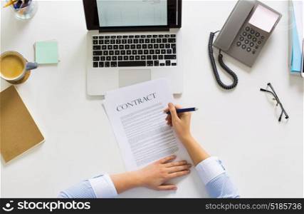 business, people and work concept - hands of businesswoman signing contract document sitting at office table. businesswoman signing contract document at office