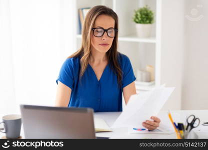 business, people and work concept - happy smiling woman with laptop computer working and writing to notebook at office or home. happy woman with papers and laptop at office