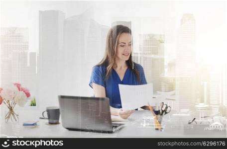 business, people and work concept - happy smiling woman with laptop computer working and writing to notebook at office over city buildings background and double exposure effect. happy woman with papers and laptop at office