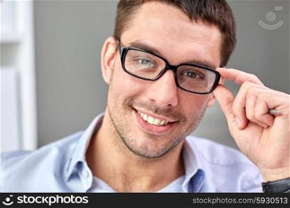 business, people and work concept - portrait of smiling businessman in eyeglasses face in office