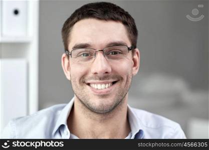 business, people and work concept - portrait of smiling businessman in eyeglasses in office