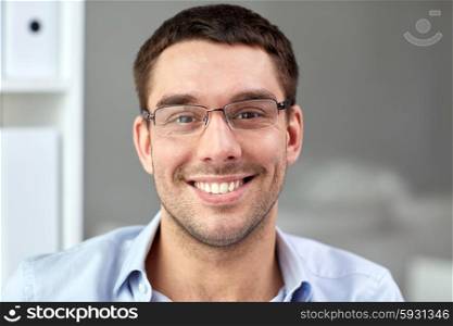 business, people and work concept - portrait of smiling businessman in eyeglasses in office
