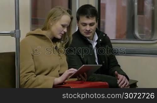 Business people are working using tablet PC while riding a metro.