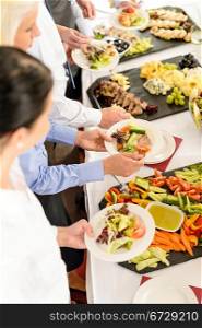 Business people around buffet table catering food at company event
